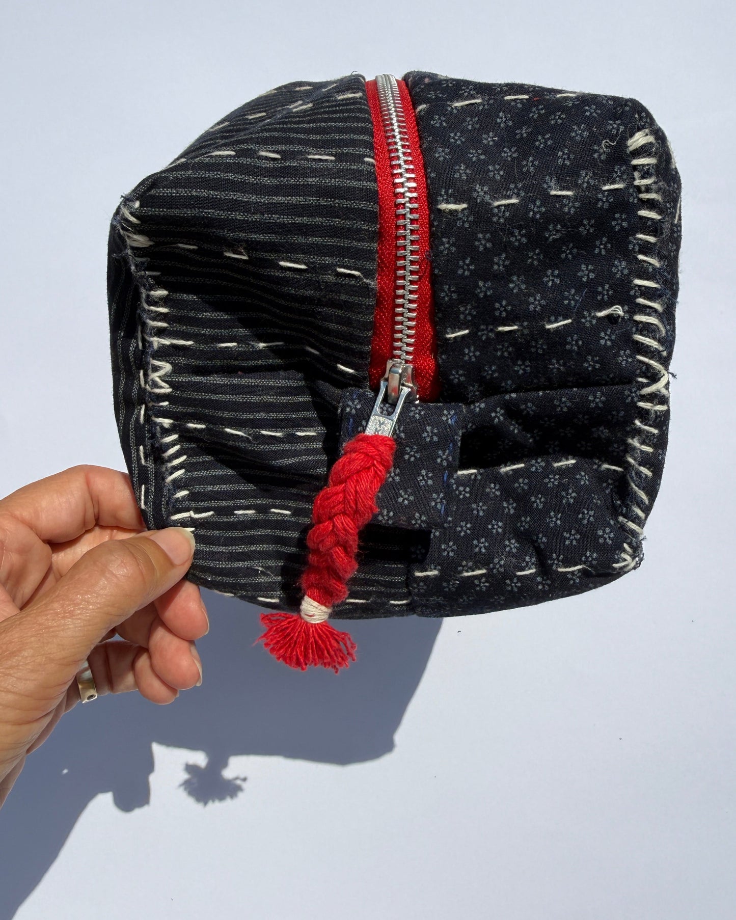 A handmade fabric metal zippered pouch with a dark navy and white Japanese fabric and quilted design.